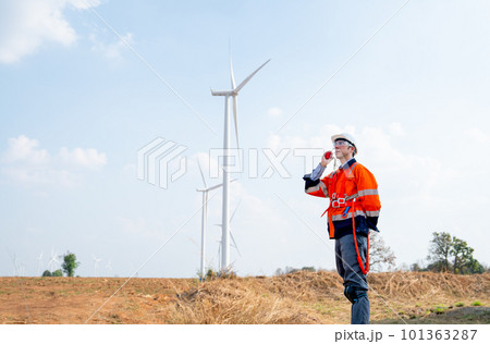 Engineer or technician worker use walkie talkie to communicate his co-worker in front windmill Engineer or technician worker use walkie talkie to communicate his co-worker in front windmill 101363287