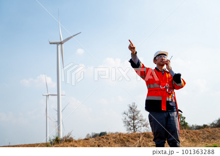 Engineer or technician worker use walkie talkie to contact and stand in front of windmill 101363288