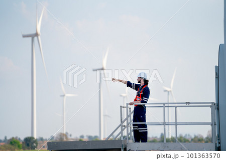 Engineer man or technician worker stand on base of windmill or wind turbine and point to left side 101363570