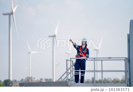 Engineer man or technician worker stand on base of windmill or wind turbine and point to left side 101363571