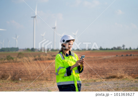 Pretty engineer or technician woman with safety protection equipment stand with using mobile phone Pretty engineer or technician woman with safety protection equipment stand with using mobile phone 101363627