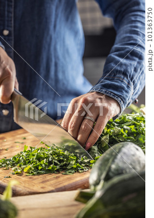 Seasonal greens use in the kitchen as woman chops parsley for freezing and later use in the winter 101363750