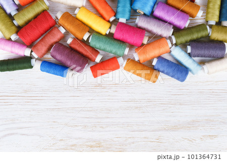 Multicolor sewing threads on white wooden background 101364731