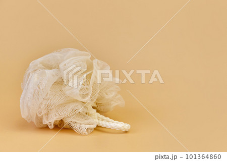 Beige mesh pouf bath sponge washcloth, single object on beige background Beige mesh pouf bath sponge washcloth, single object on beige background 101364860
