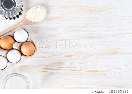 Baking ingredients flour, eggs, milk, bakeware on white wooden background with copy space 101365151