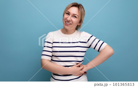 attractive blond young woman in green silk shirt laughing on blue background 101365813