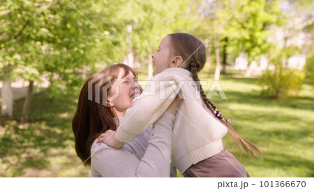 happy family. mom hugs child girl daughter park. cheerful girl spinning her mother arms. happy child. child dream mom. kid laughs his mother arms park. happy family concept. child runs green grass 101366670