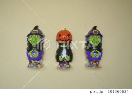 cute witch and pumpkins stand on a light background in close-up. Halloween concept. Holiday decorations cute witch and pumpkins stand on a light background in close-up. Halloween concept. Holiday decorations 101366684