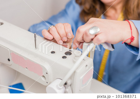Atelier process needle detail. Unrecognizable woman hand on a sewing machine doing handmade fabric Atelier process needle detail. Unrecognizable woman hand on a sewing machine doing handmade fabric 101368371