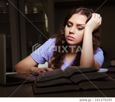 Young female student preparing for exams late at home 101370295