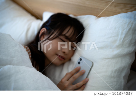 スマホを使いながら寝落ちする若い女性 スマホを使いながら寝落ちする若い女性 101374037