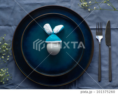 Festive Easter table setting with egg and flowers on blue background 101375260
