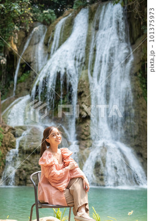 Young Asian woman sitting on a chair In front of the Khoun Moung Keo Waterfall Young Asian woman sitting on a chair In front of the Khoun Moung Keo Waterfall 101375973