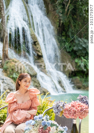 Young Asian woman sitting on a chair In front of the Khoun Moung Keo Waterfall Young Asian woman sitting on a chair In front of the Khoun Moung Keo Waterfall 101375977