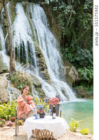 Young Asian woman sitting on a chair In front of the Khoun Moung Keo Waterfall Young Asian woman sitting on a chair In front of the Khoun Moung Keo Waterfall 101375982
