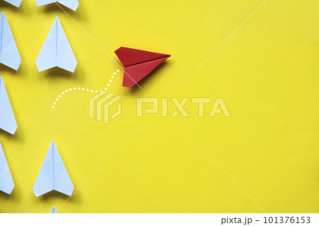 Top view of red paper airplane origami leaving other white airplanes on yellow background with customizable space for text or ideas. Leadership skills concept and copy space. 101376153
