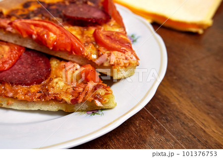 Pieces of pepperoni pizza on a white plate close up Pieces of pepperoni pizza on a white plate close up 101376753