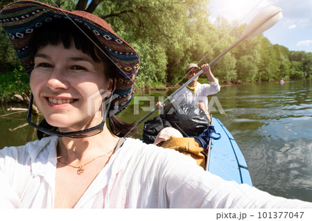 Man and woman couple, baby is sleeping, selfies are happy in family kayak trip rowing boat on the river, water hike, a summer adventure. Eco-friendly and extreme tourism, active and healthy lifestyle 101377047
