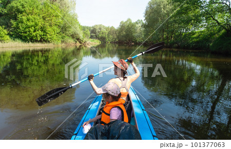 Family kayak trip. Mom and daughter rowing a boat on the river, a water hike, a summer adventure. Eco-friendly and extreme tourism, active and healthy lifestyle Family kayak trip. Mom and daughter rowing a boat on the river, a water hike, a summer adventure. Eco-friendly and extreme tourism, active and healthy lifestyle 101377063
