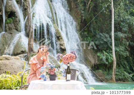 Young Asian woman sitting on a chair In front of the Khoun Moung Keo Waterfall Young Asian woman sitting on a chair In front of the Khoun Moung Keo Waterfall 101377399