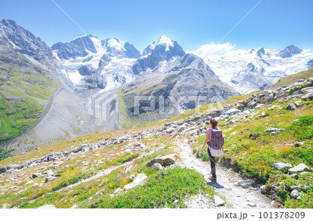 A woman alone walks on high mountain trail 101378209