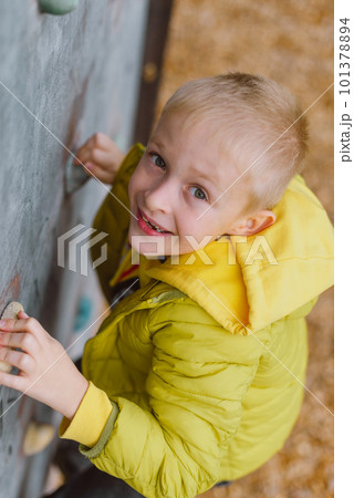Boy At The Climbing Wall Without A Helmet, Danger At The Climbing Wall. Little Boy Climbing A Rock Wall Indoor 101378894