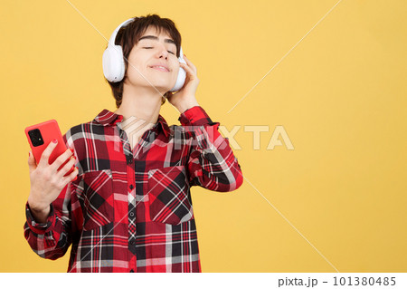 Relaxed androgynous person listening to music with mobile and headphones 101380485