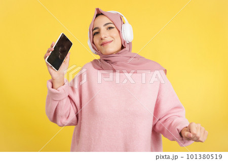 Happy muslim woman dancing and listening to music with mobile Happy muslim woman dancing and listening to music with mobile 101380519
