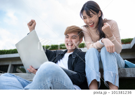 Asian students sitting on step are excited and happy after check exam results in computer laptops, Happy entrepreneurs feel good after Project success. Student lifestyle in university 101381236