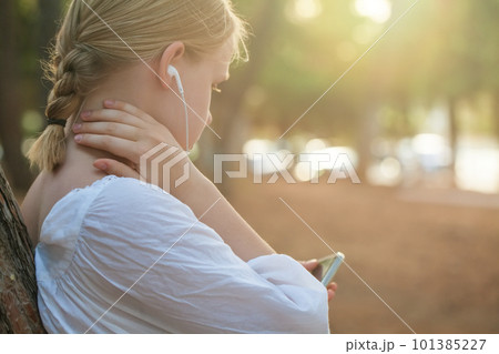 Portrait of teenage girl in white shirt and headphones typing on mobile phone 101385227