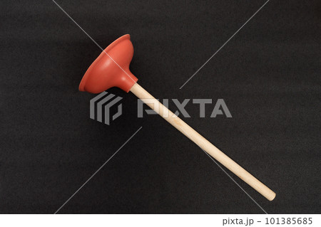 Red toilet plunger with wooden handle isolated on black background. Professional plumber tool. 101385685