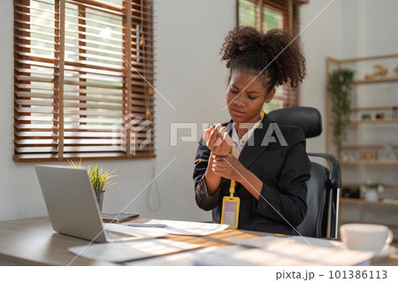 Wrist pain, business woman and muscle injury while sitting at desk and working as a data analyst. Hand of a black female entrepreneur suffering from carpal tunnel syndrome or arthritis in office Wrist pain, business woman and muscle injury while sitting at desk and working as a data analyst. Hand of a black female entrepreneur suffering from carpal tunnel syndrome or arthritis in office 101386113