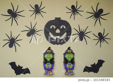 Scary Halloween figurines stand on a light background in close-up, behind hangs terrible pumpkin, spiders and bat 101386585
