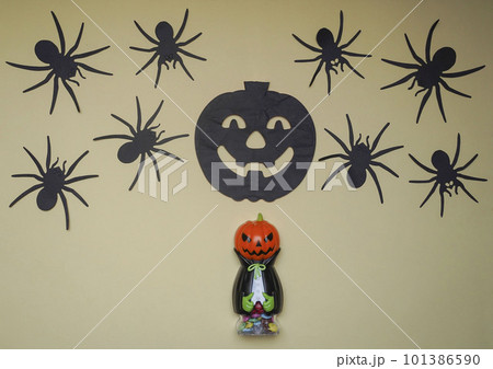 Scary Halloween figurines stand on a light background close-up, behind hangs terrible black pumpkin and spiders 101386590