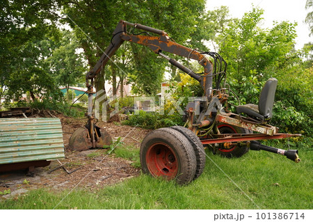Mini excavator digging earth in field or forest. Laying underground sewer pipes during the construction of a house. Digging trenches for gas pipeline or oil pipeline. Earthwork, foundation pit. 101386714