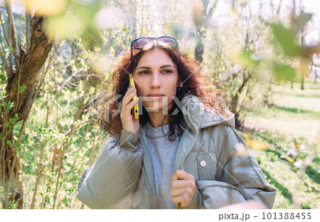 Young brunette woman talking on the phone in spring in the park 101388455