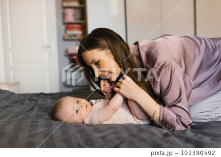 Happy mother having fun and laughing with her baby on the bed Happy mother having fun and laughing with her baby on the bed 101390592