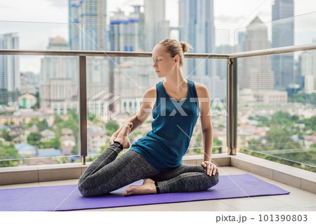 Young woman is practicing yoga in the morning on her balcony with a panoramic view of the city and skyscrapers 101390803