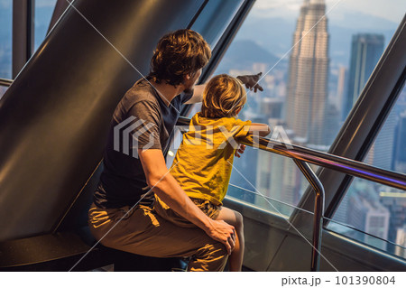 Dad and son are looking at Kuala lumpur cityscape. Panoramic view of Kuala Lumpur city skyline evening at sunset skyscrapers building in Malaysia. Traveling with kids concept Dad and son are looking at Kuala lumpur cityscape. Panoramic view of Kuala Lumpur city skyline evening at sunset skyscrapers building in Malaysia. Traveling with kids concept 101390804