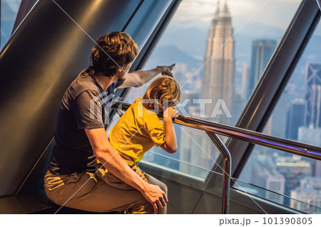 Dad and son are looking at Kuala lumpur cityscape. Panoramic view of Kuala Lumpur city skyline evening at sunset skyscrapers building in Malaysia. Traveling with kids concept 101390805