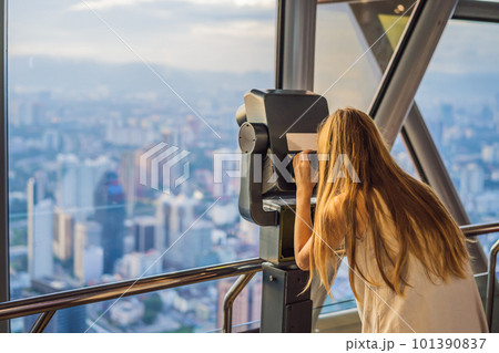 Woman looks at Kuala lumpur cityscape. Panoramic view of Kuala Lumpur city skyline evening at sunset skyscrapers building in Malaysia Woman looks at Kuala lumpur cityscape. Panoramic view of Kuala Lumpur city skyline evening at sunset skyscrapers building in Malaysia 101390837