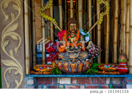 Bronze buddha statue sitting in meditation with flower decorations for festival ceremony.  101391158