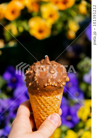 Female hand holding delicious american vanilla chocolate ice cream. Tasty homemade icecream Gelato in the waffle cone. Gluten free vegan dairy free 101391212