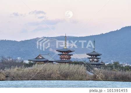 山焼きの終わった黒い若草山と夕暮れの薬師寺と月の風景 101391455