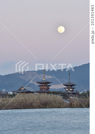 山焼きの終わった黒い若草山と夕暮れの薬師寺と月の風景 101391465