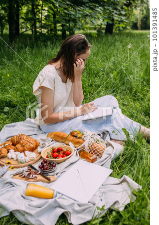 Beautiful woman on picnic. She smiles, eats strawberries and enjoys summer. 101391485