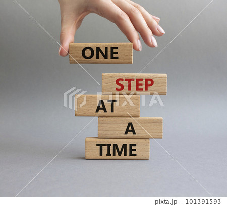 One step at a time symbol. Concept words One step at a time on wooden blocks. Beautiful grey background. Businessman hand. Business and One step at a time concept. Copy space. 101391593