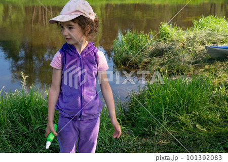 Girl sprays mosquito spray on the skin in nature that bite her hands and feet. Protection from insect bites, repellent safe for children. Outdoor recreation, against allergies. Summer time 101392083