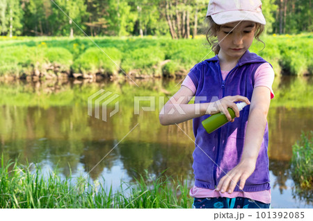 Girl sprays mosquito spray on the skin in nature that bite her hands and feet. Protection from insect bites, repellent safe for children. Outdoor recreation, against allergies. Summer time Girl sprays mosquito spray on the skin in nature that bite her hands and feet. Protection from insect bites, repellent safe for children. Outdoor recreation, against allergies. Summer time 101392085