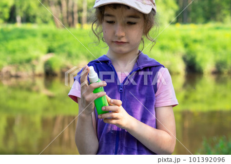 Girl sprays mosquito spray on the skin in nature that bite her hands and feet. Protection from insect bites, repellent safe for children. Outdoor recreation, against allergies. Summer time Girl sprays mosquito spray on the skin in nature that bite her hands and feet. Protection from insect bites, repellent safe for children. Outdoor recreation, against allergies. Summer time 101392096